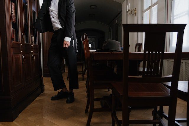 A person standing beside a wooden table and chairs