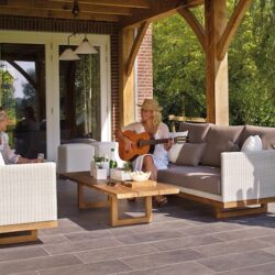 Two women sitting outdoors, playing the guitar.